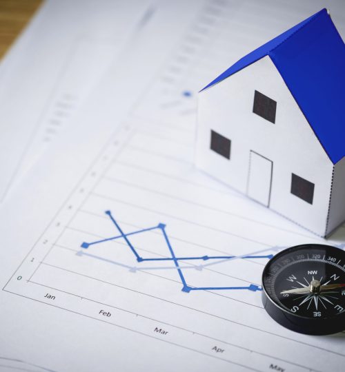 House model and compass on plan background, Real estate concept.